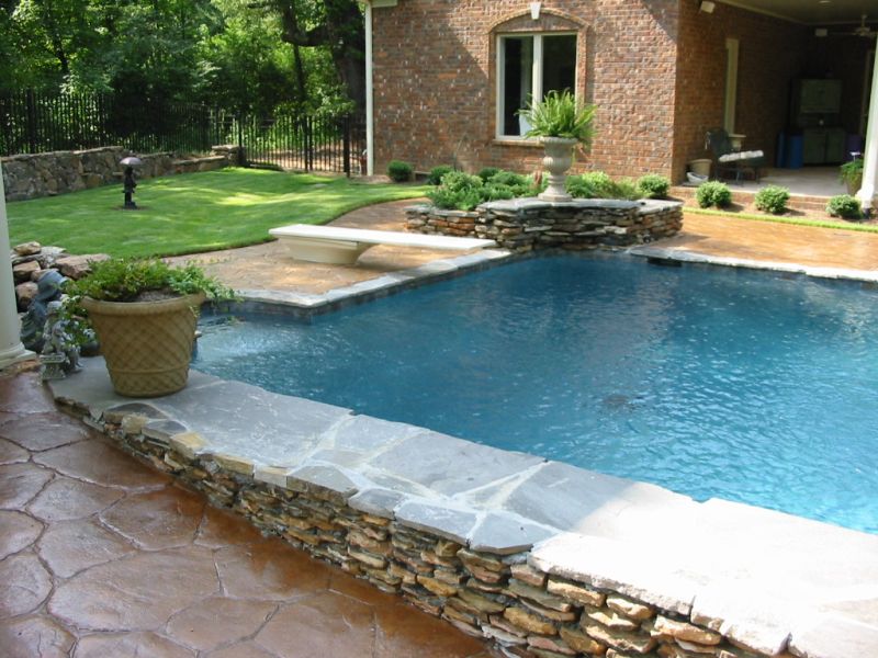 Pool with decorative concrete deck and natural stone accent.