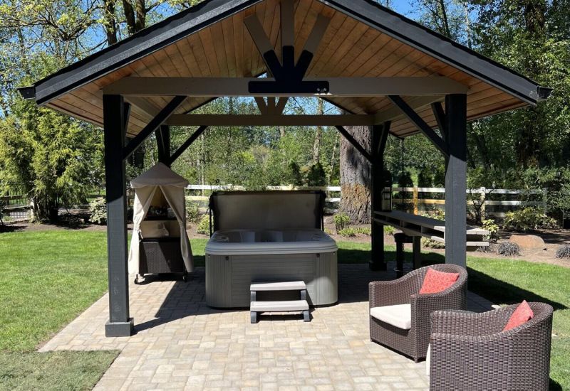 A pergola built for an outdoor spa on paver bricks.